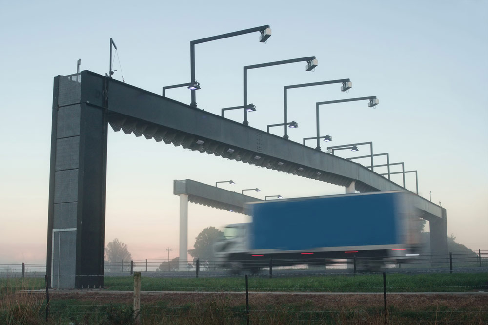 Niebieska ciężarówka przejeżdżająca przez punkt pobierania opłat bez zatrzymywania TOLL - e-tollgps.pl
